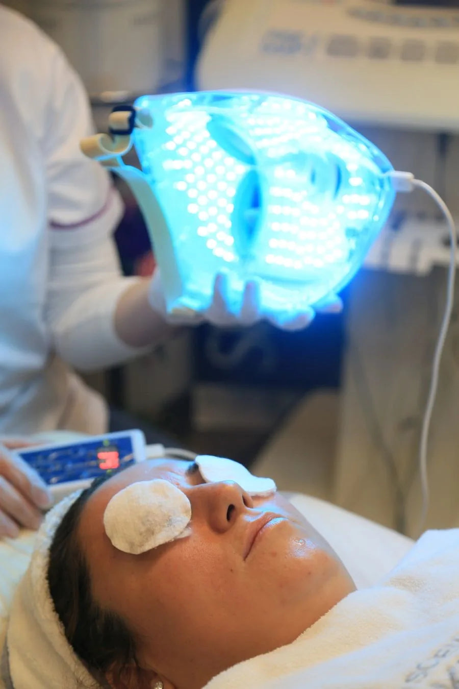Mujer recibiendo tratamiento de terapia LED facial en spa de lujo